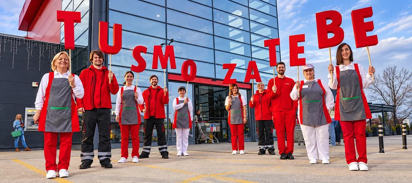Konzum store staff holding letters spelling a welcome message outside a store