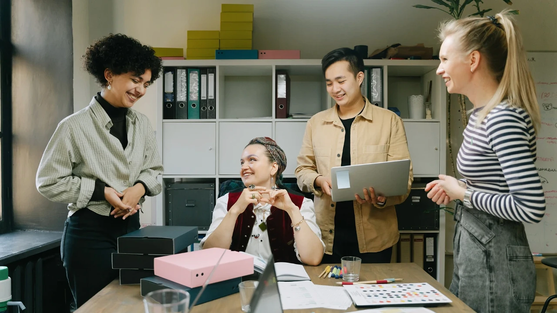 Colleagues talking beside a desk with a laptop and office files